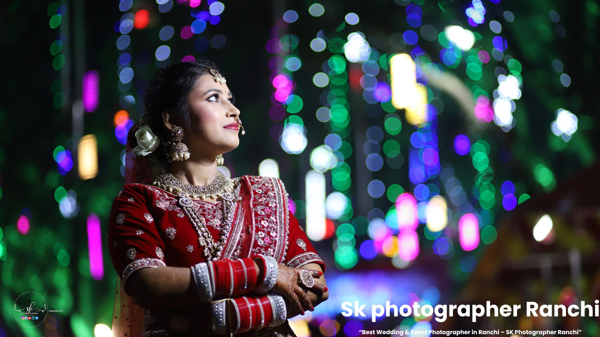 Indian bride in red bridal lehenga posing with colorful wedding lights in the background, captured by a leading Wedding Photographer in Ranchi.