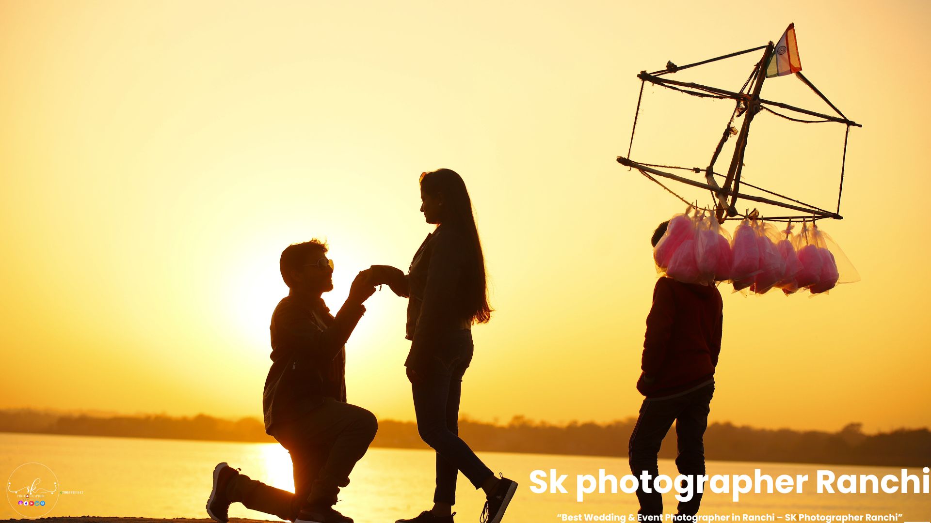 Sunset proposal moment by a couple near lakeside with cotton candy seller passing, captured by a prewedding photographer in Ranchi.