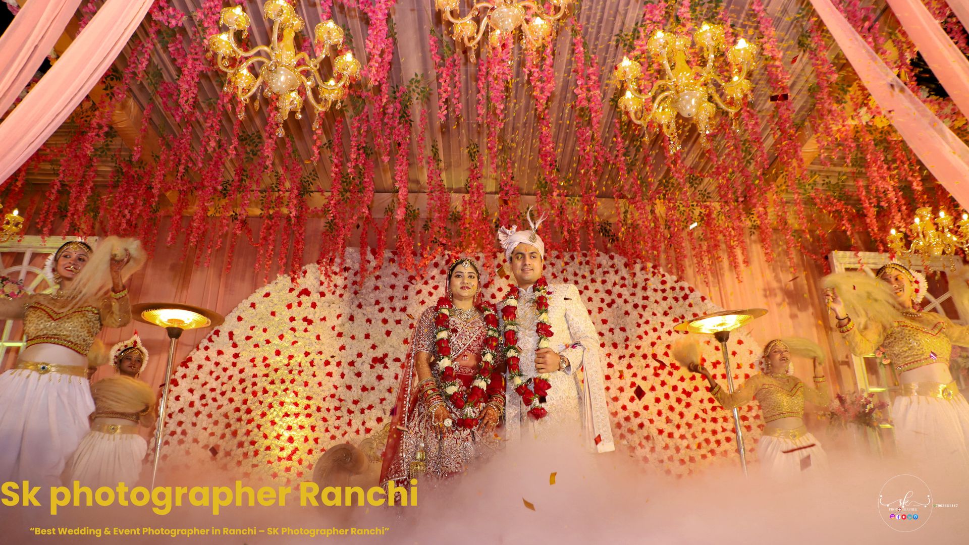 Grand Indian wedding stage with bride and groom posing under floral decorations and chandeliers, captured by a Wedding Photographer in Ranchi.